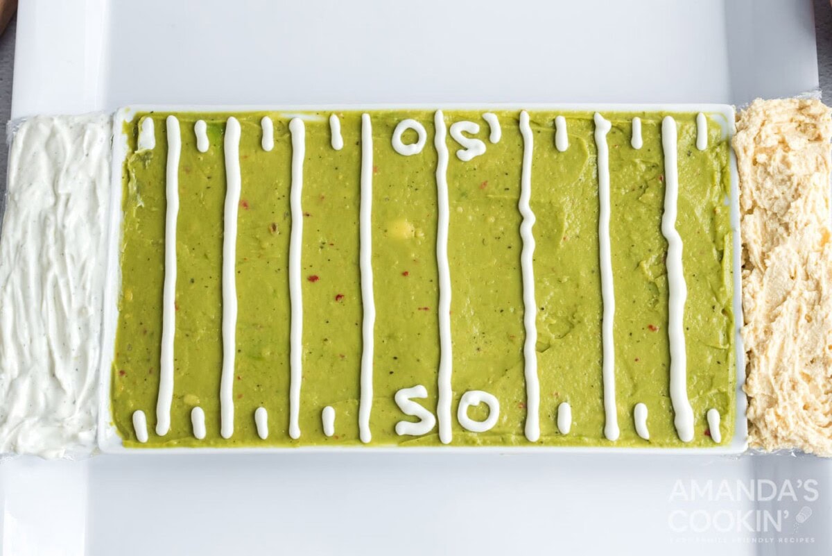 guacamole, french onion dip, and hummus on a tray with sour cream outline of football field