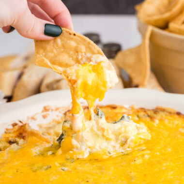 chip pulling spinach dip from bowl