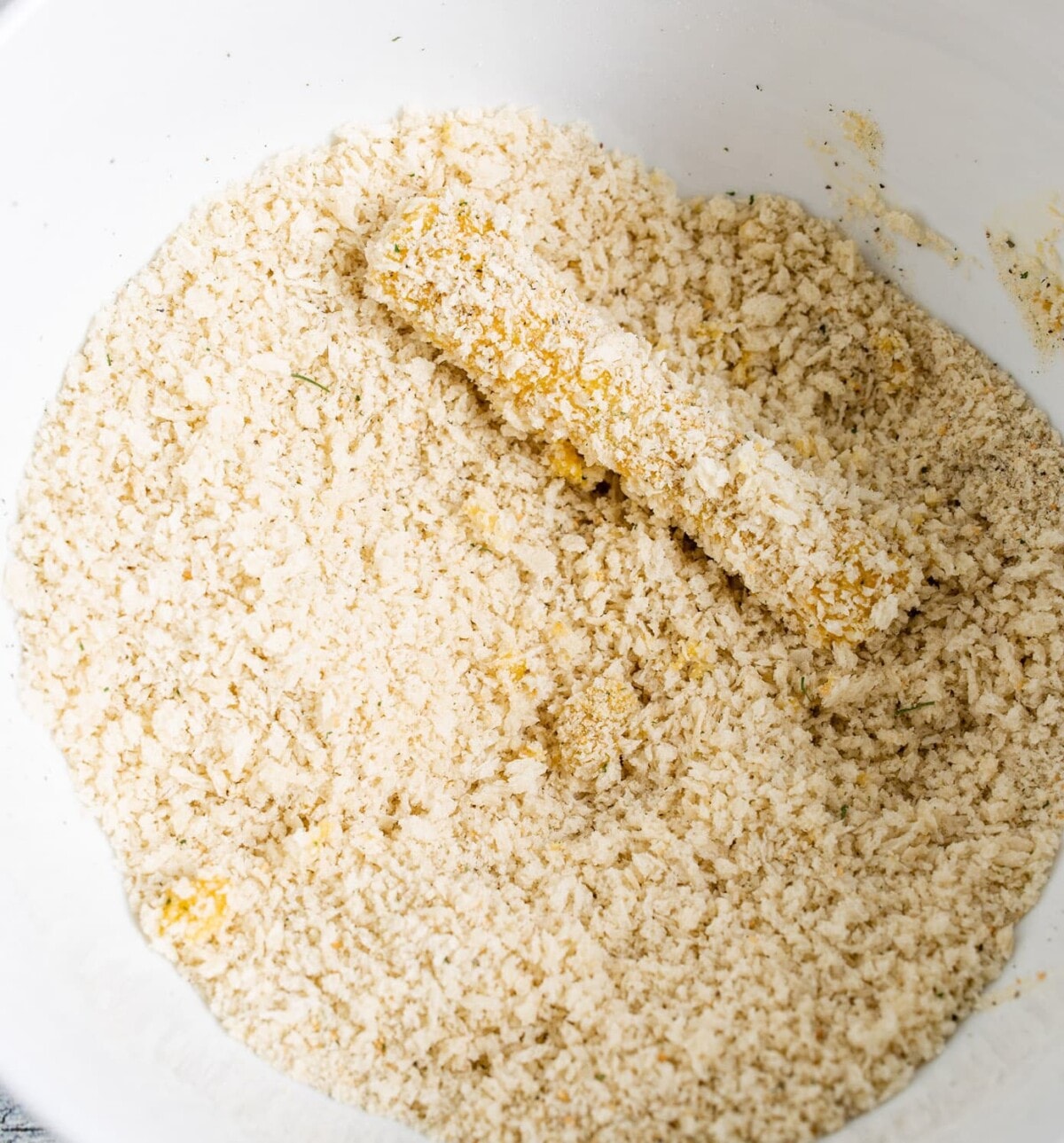 cheese stick in a bowl of panko crumbs