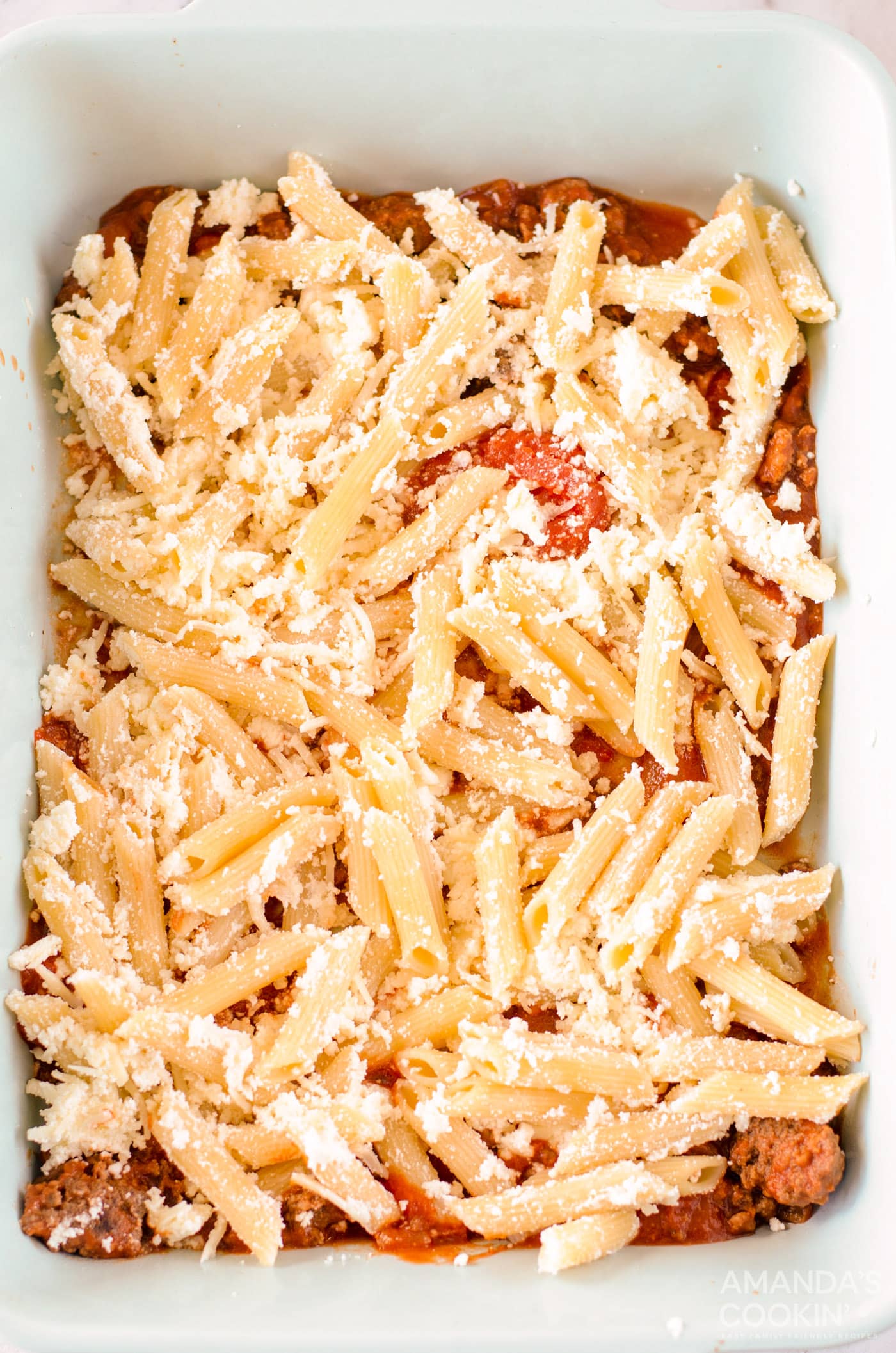 cheese and pasta mixture over meat sauce in casserole dish