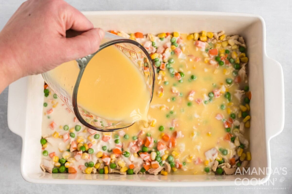 slowly pouring brother mixture on top of casserole