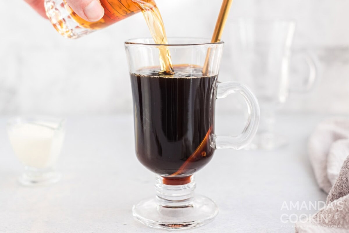 pouring Irish whiskey into mug of coffee