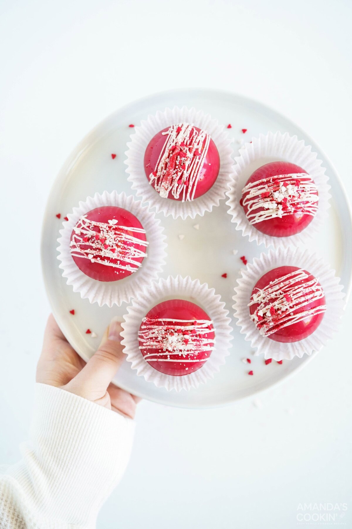 red velvet cocoa bombs in paper liners on plate