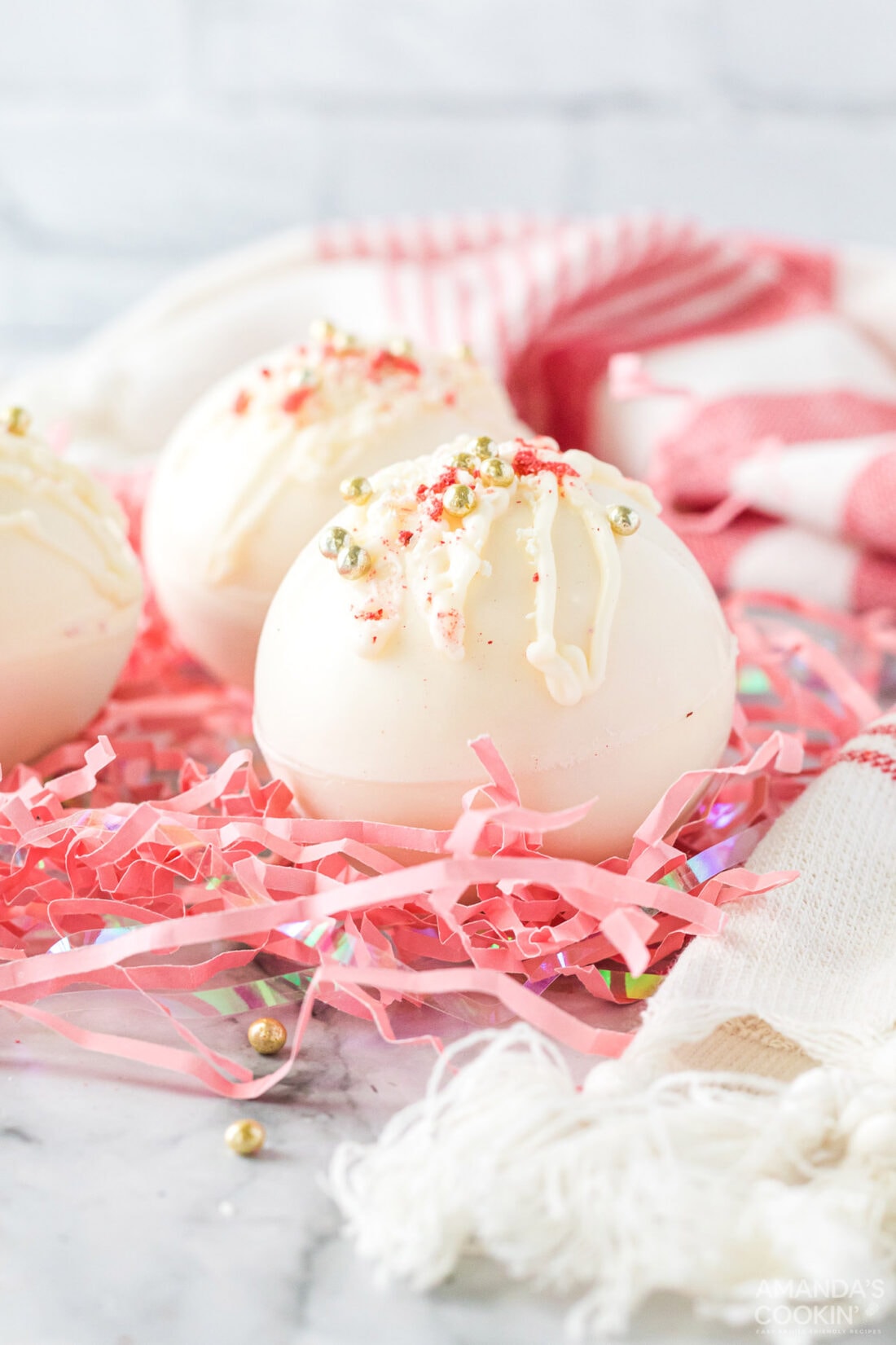 white chocolate hot cocoa bombs on pink shredded paper