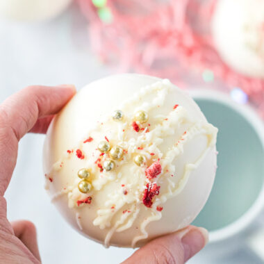 holding a white chocolate strawberry hot cocoa bombs