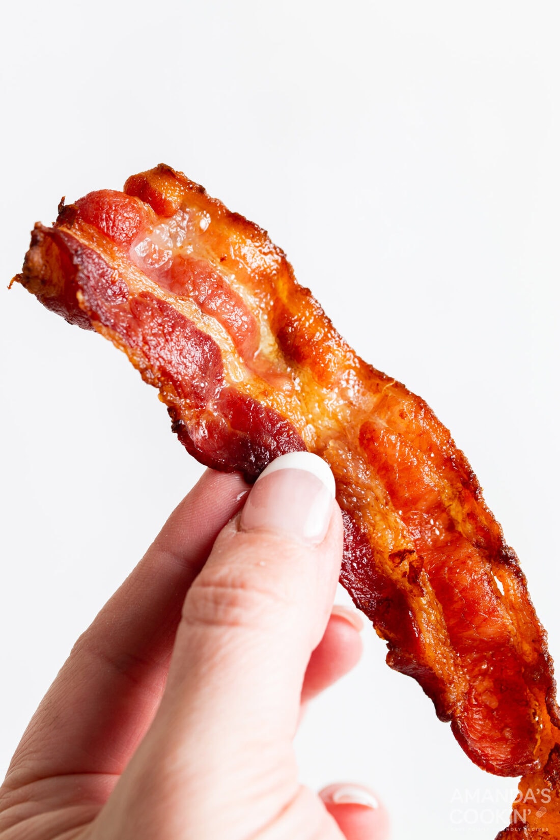 woman holding slice of bacon