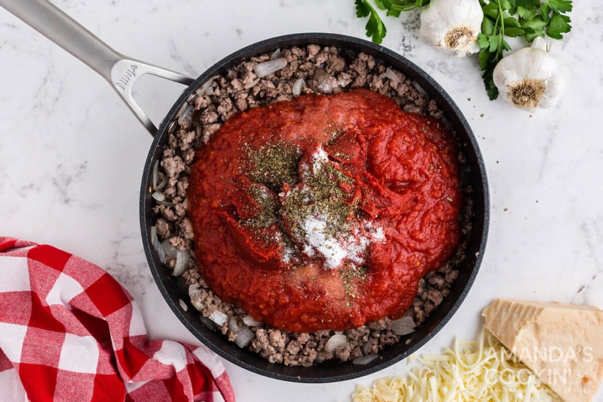 tomato sauce on top of cooked meat in a skillet