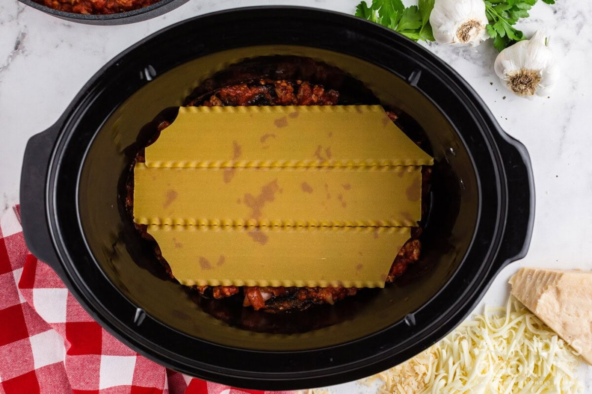 lasagna noodles on top of meat sauce in crockpot