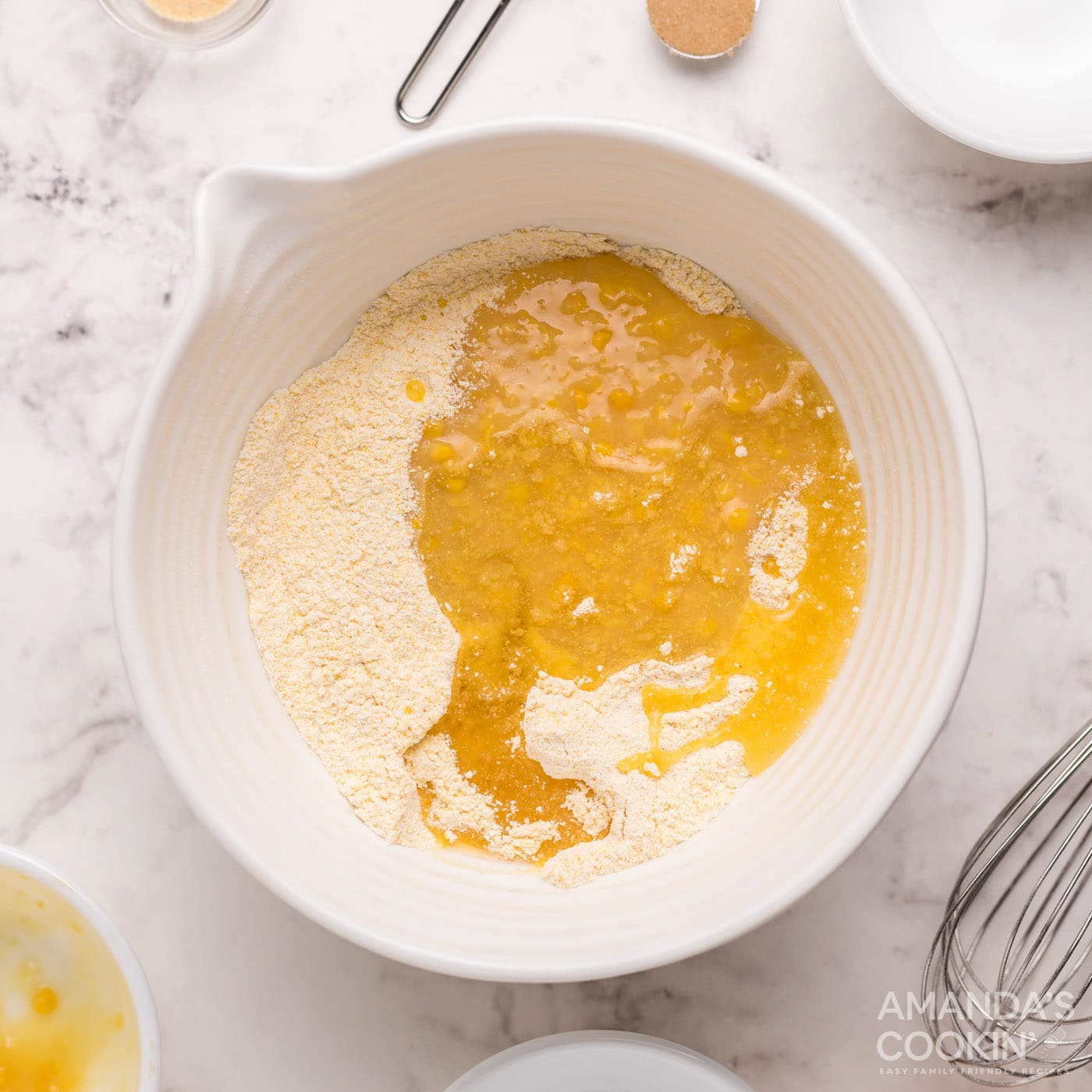cream corn and canola oil adding to cornbread mixture in bowl