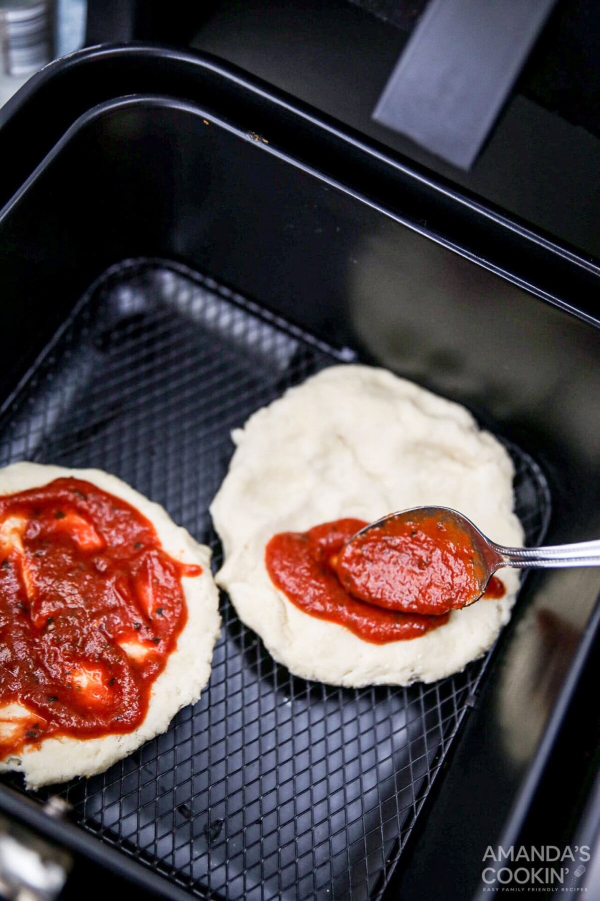 spreading sauce on pizza crust