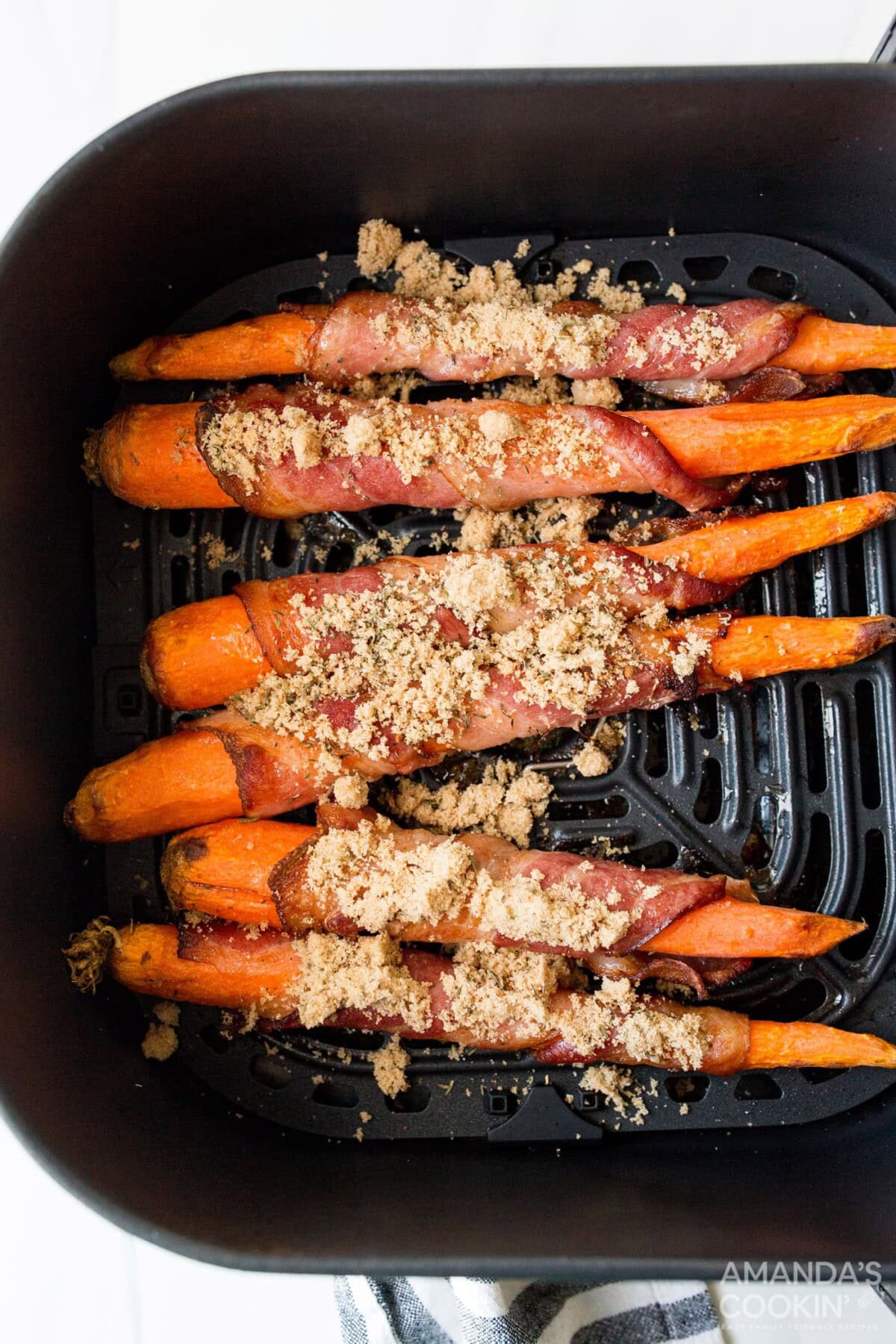 brown sugar sprinkled on bacon wrapped carrots in an air fryer