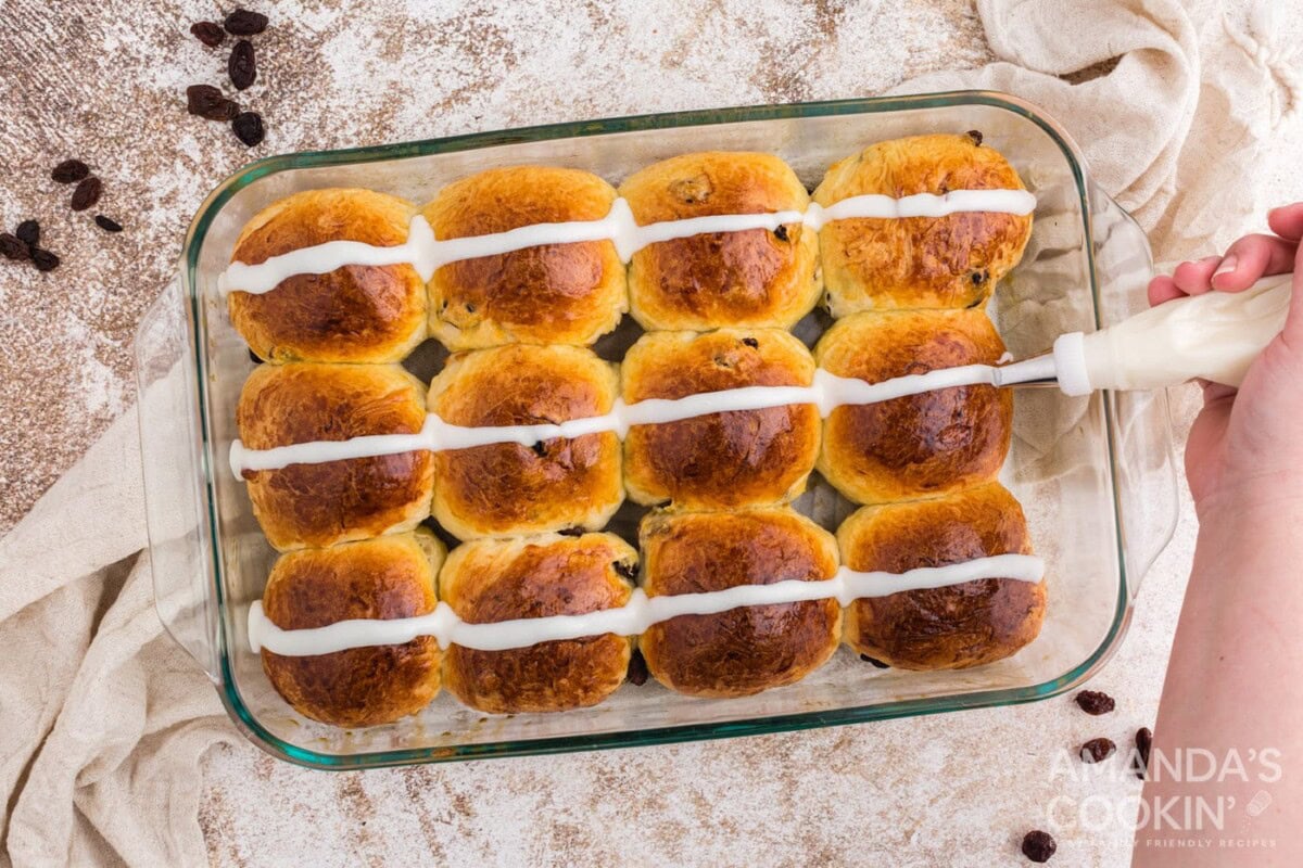 adding icing strip to buns in a pan