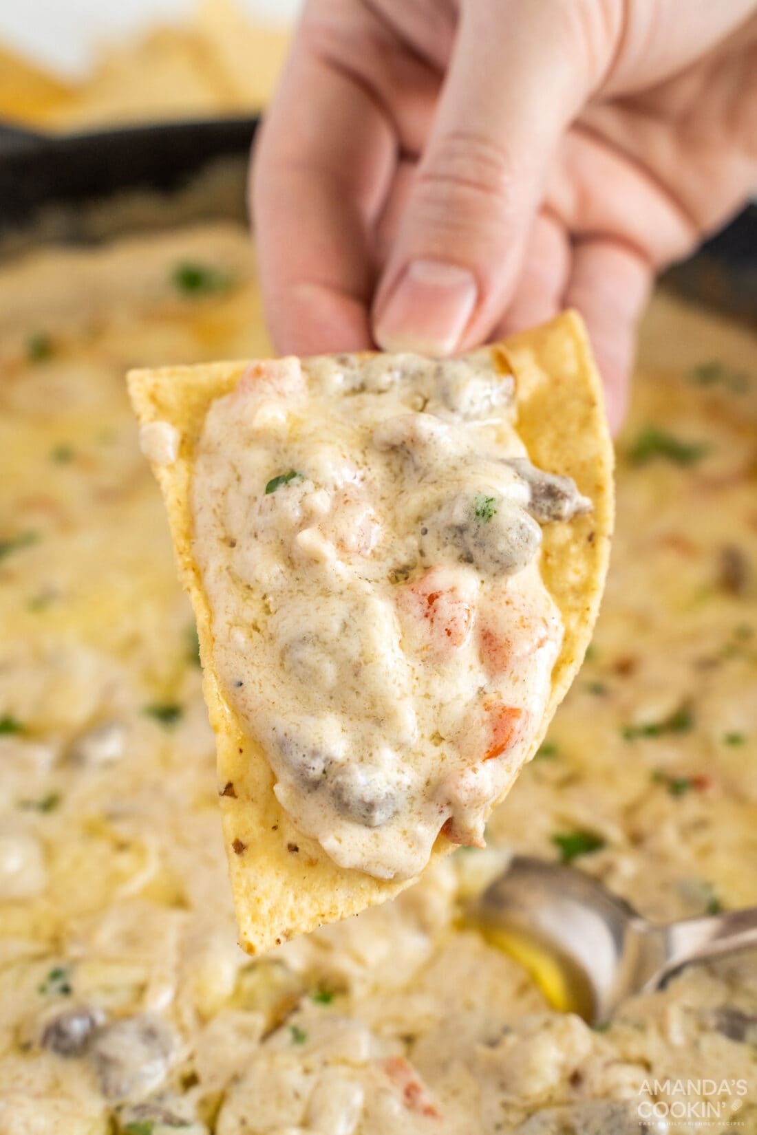 lifting Philly Cheesesteak Dip with a tortilla chip