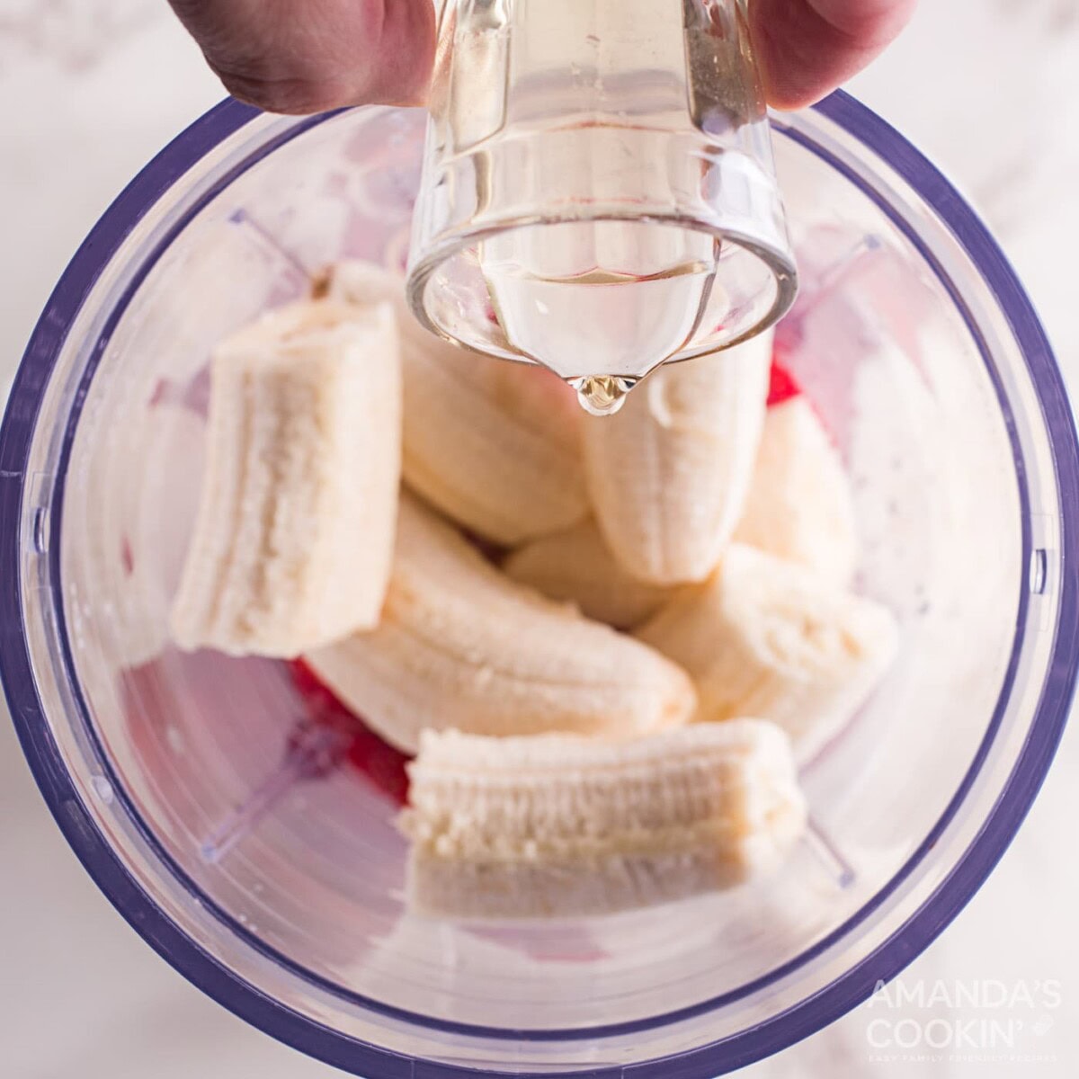 adding simple syrup to bananas and strawberries in blender