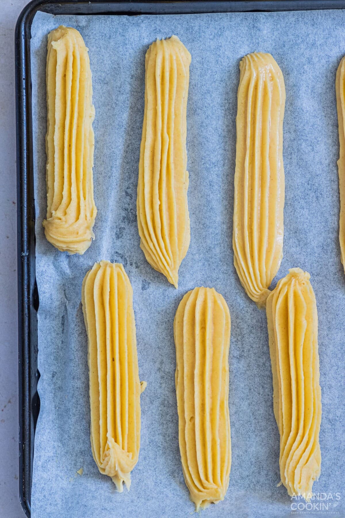 piped churro dough on a parchment lined baking sheet