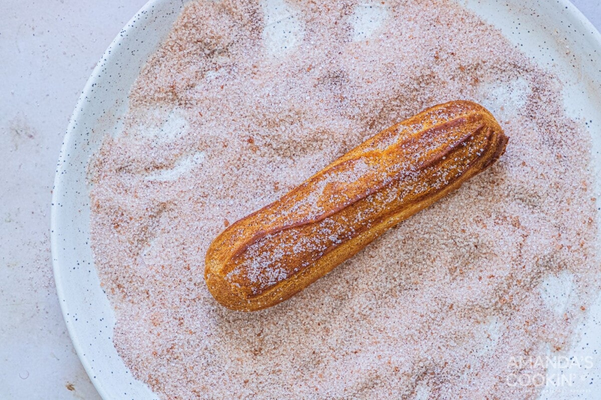 dipping churro in cinnamon sugar mixture