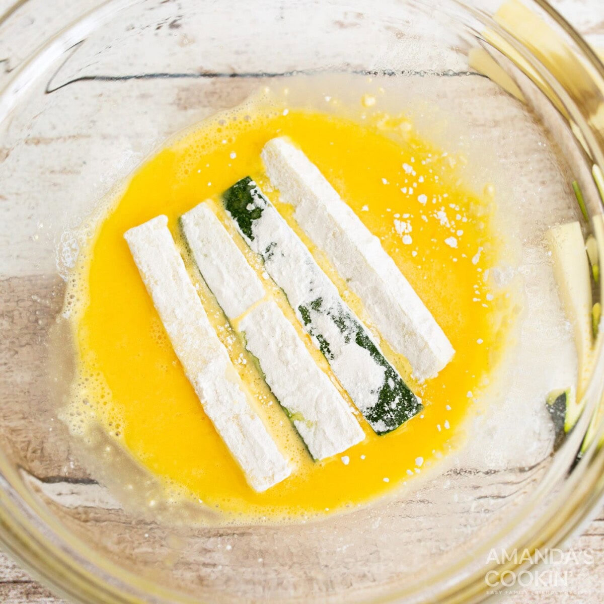 dredging flour zucchini sticks in eggwash