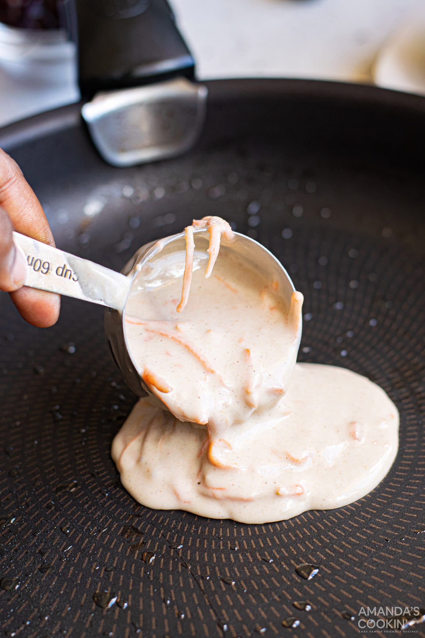 pouring carrot cake pancake batter into a skillet