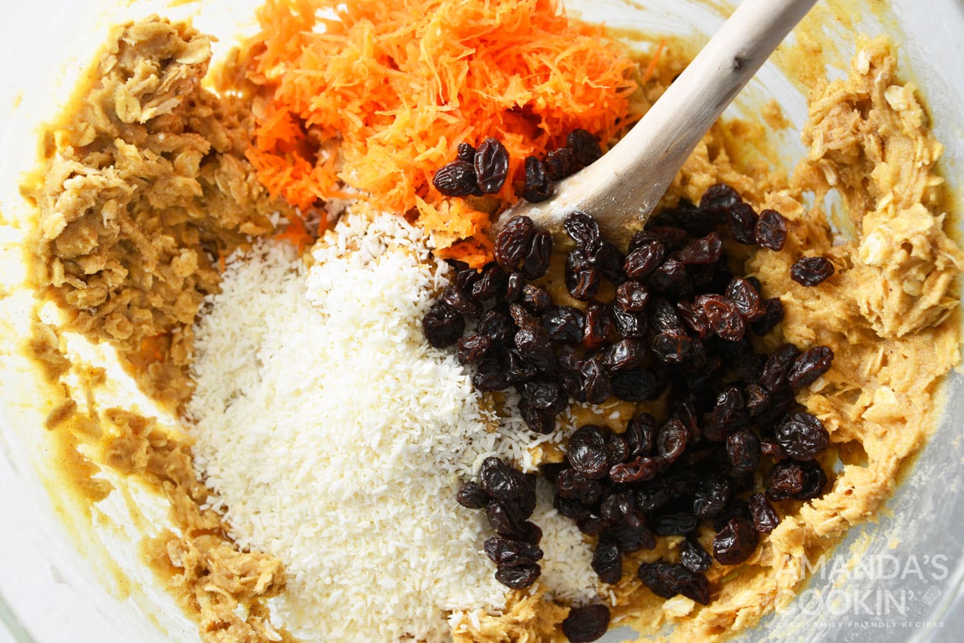 stiring in carrots, shredded coconut, and raisins to a bowl of cookie dough