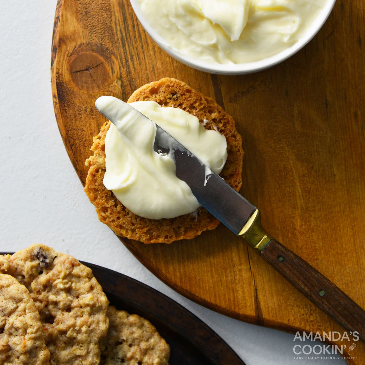 spreading cream cheese frosting onto cookie with a butter knife