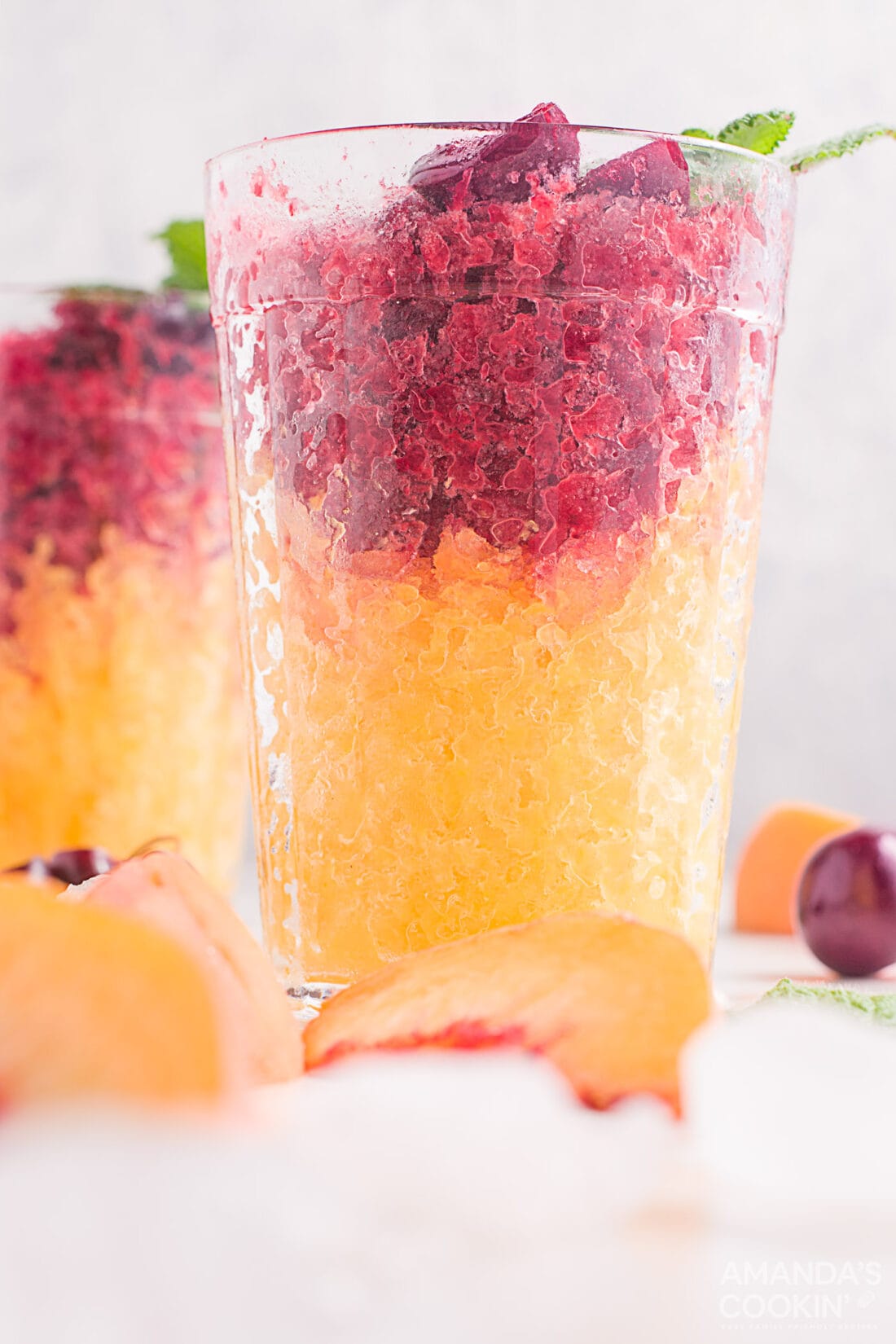 cherry and peach slushies layered in drinking glasses