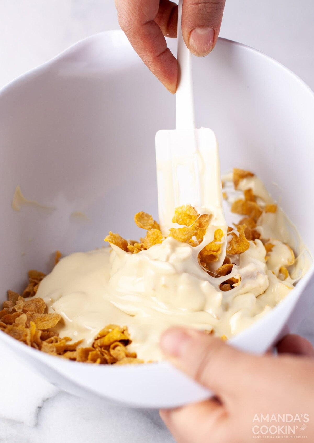 stirring white chocolate into cornflakes