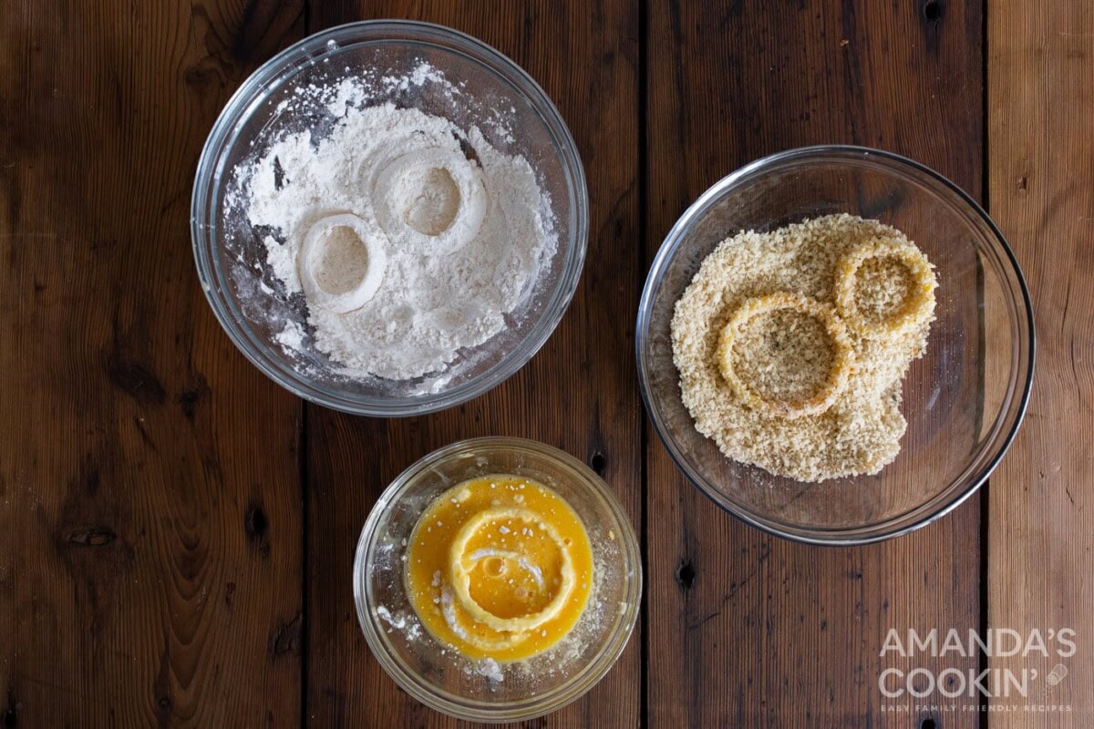dipping onion in bowl of flour, breadcrumbs, and whisked eggs