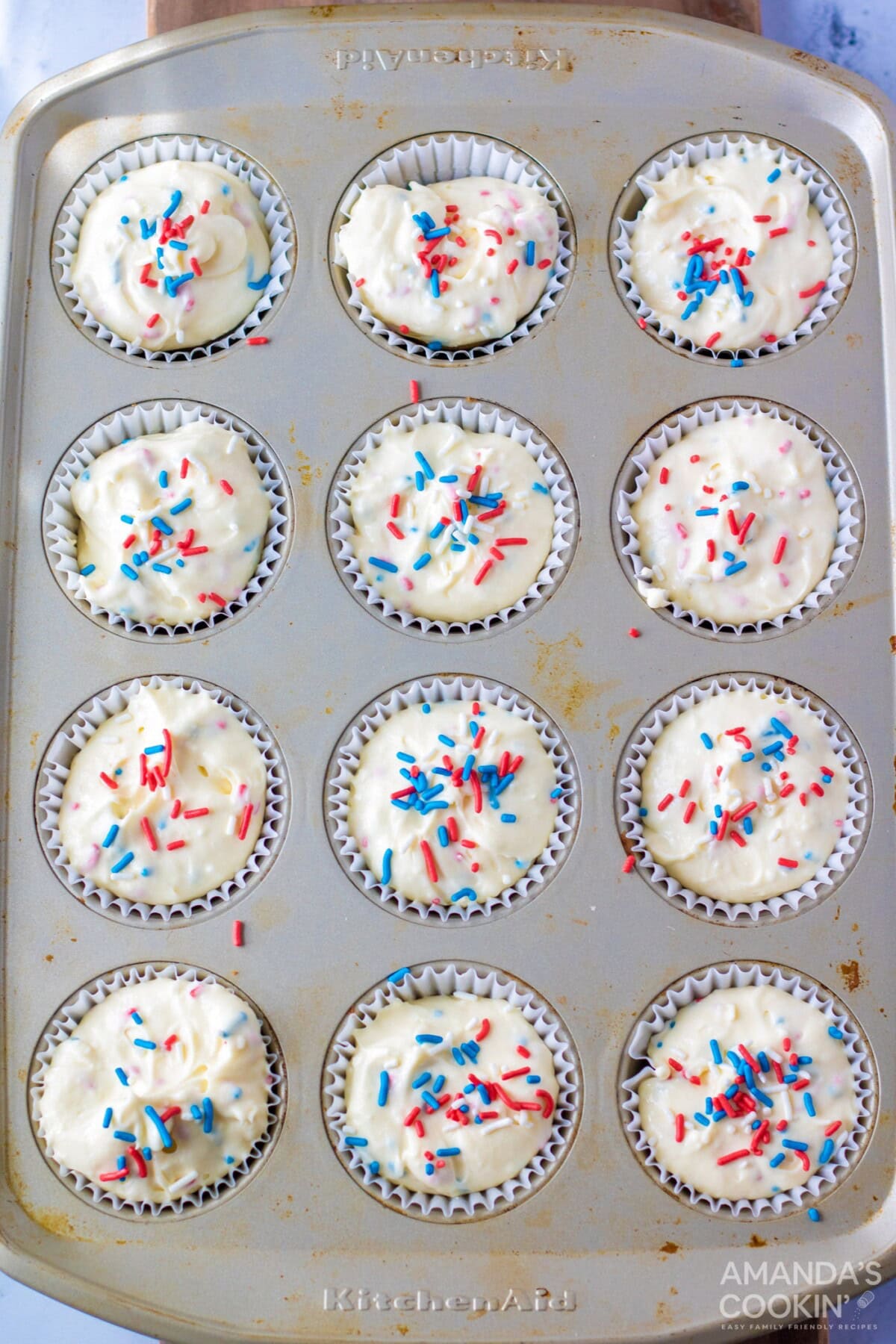 Mini cheesecake batter in a muffin tin with sprinkles