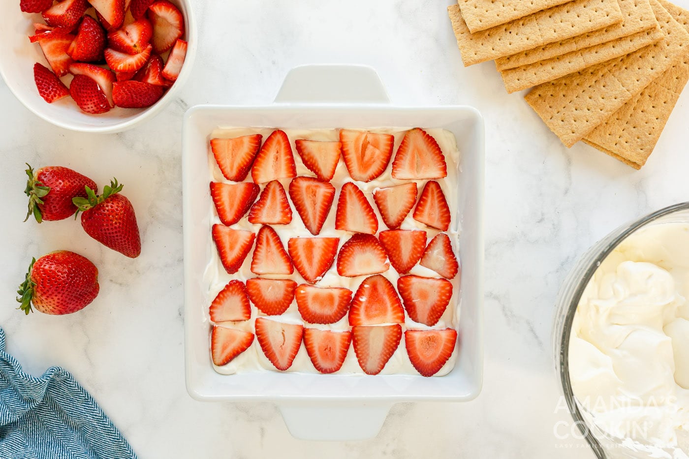 strawberries on top of whipped cream in a baking dish