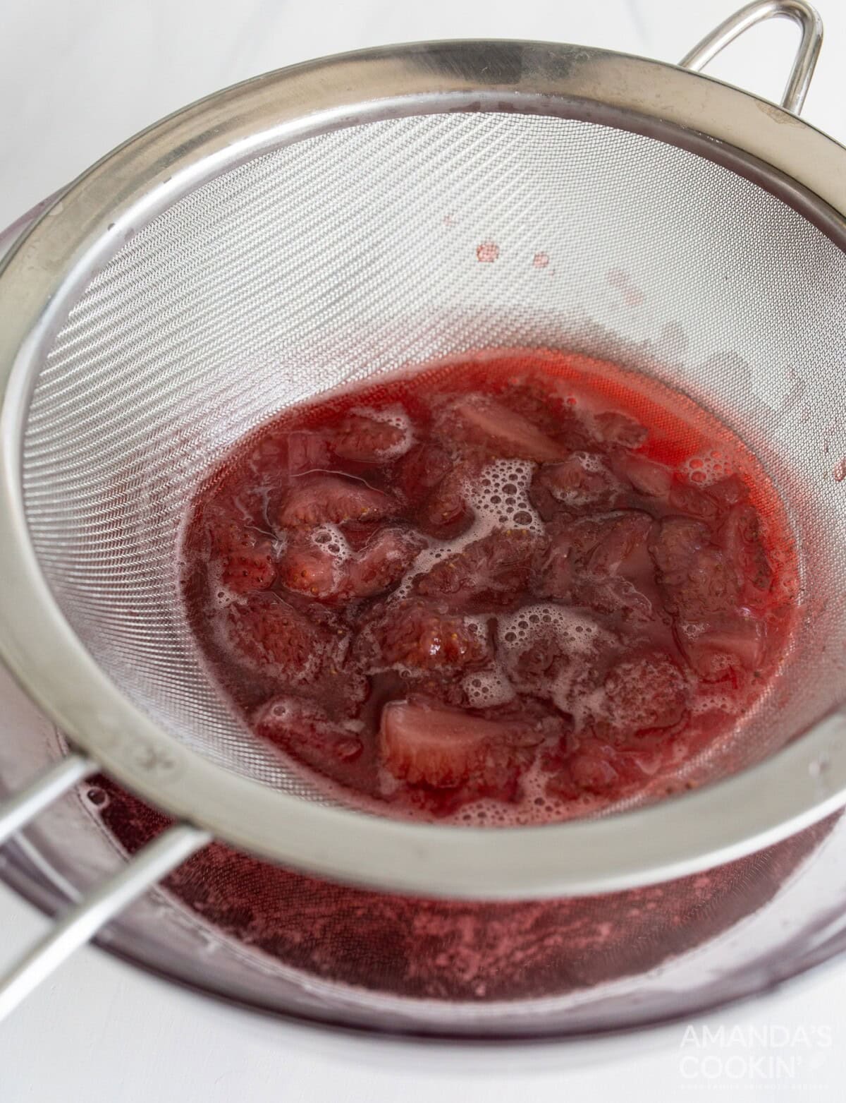strawberry simple syrup in a strainer