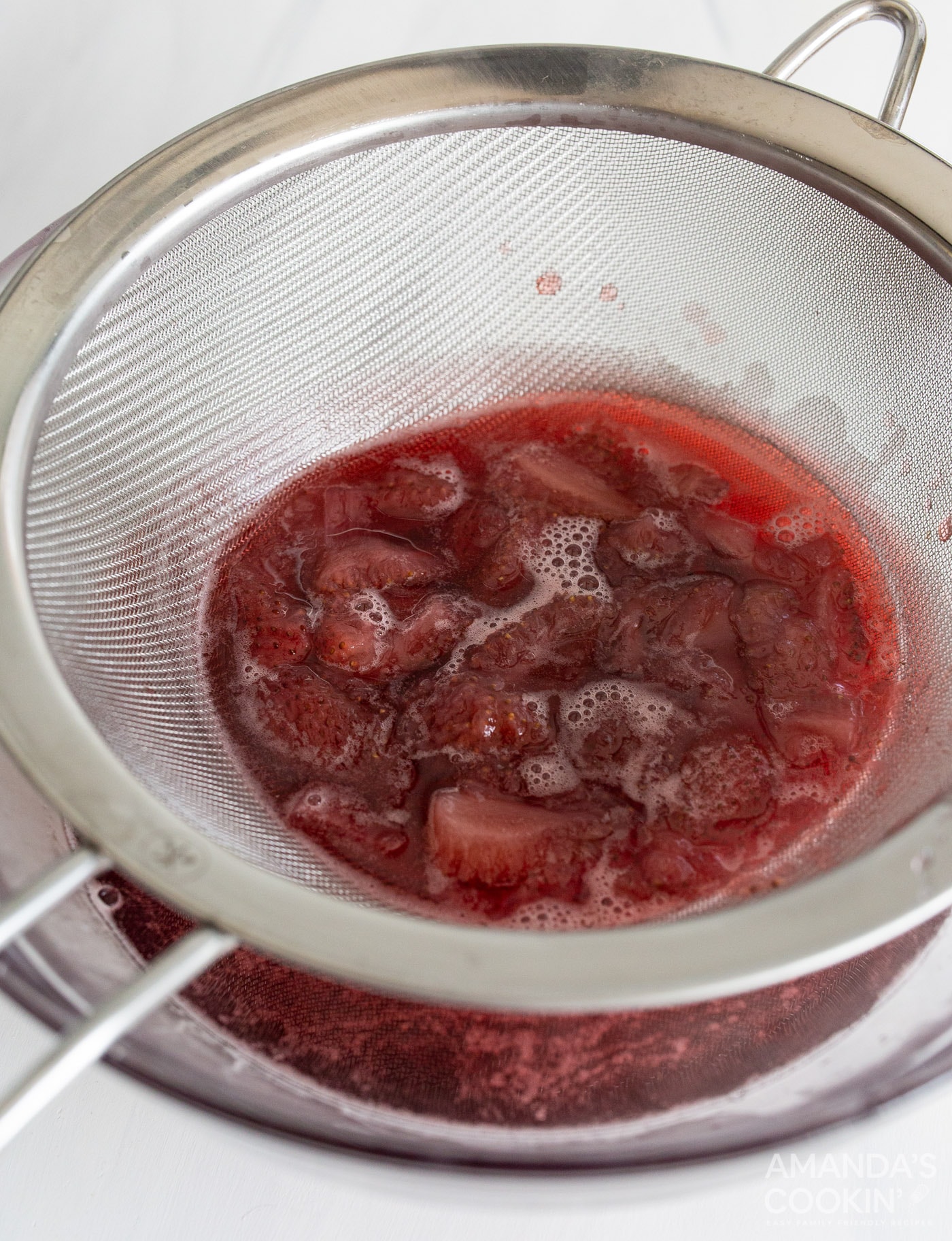 strawberry simple syrup in a strainer