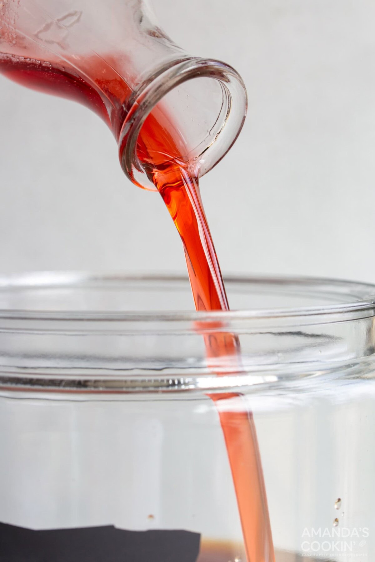 pouring strawberry simple syrup in a pitcher