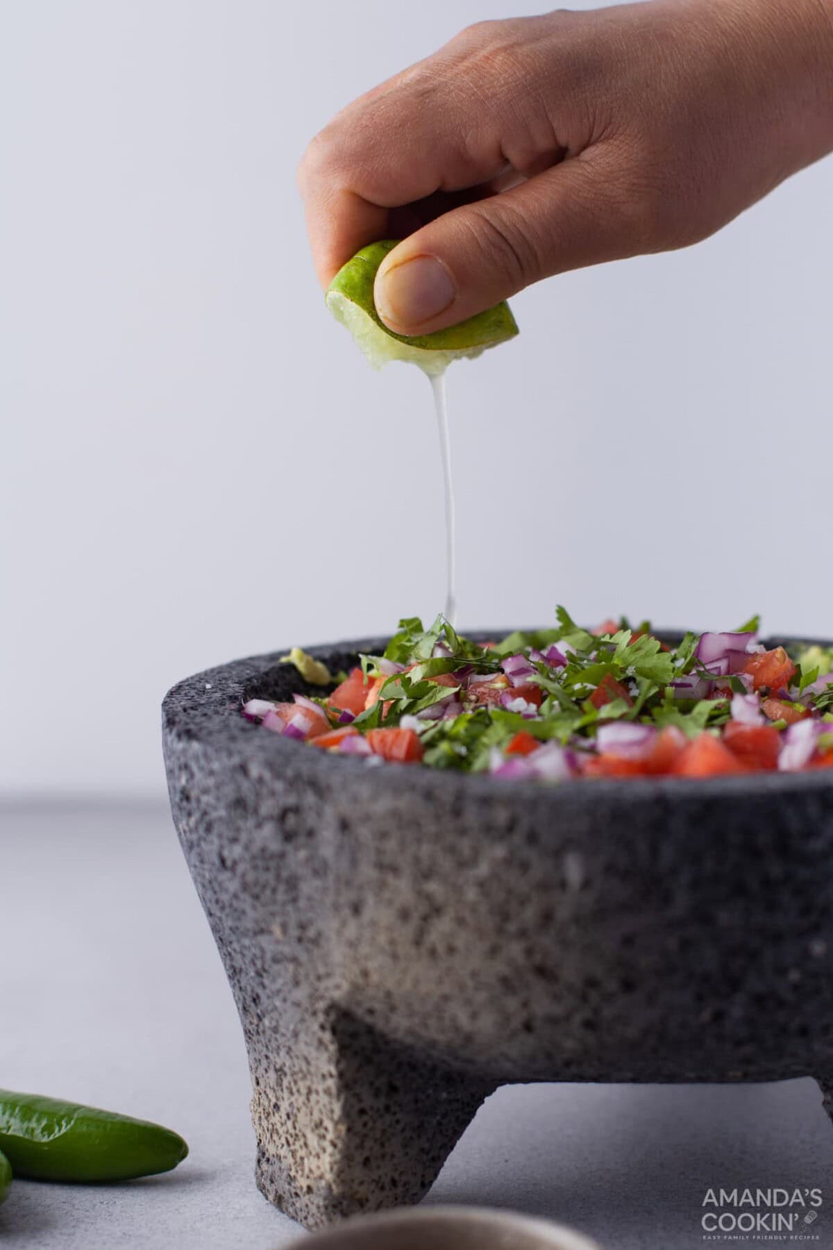hand squeezing lemon into guacamole