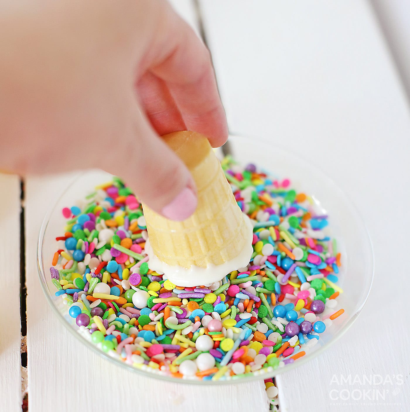 dipping chocolate coated ice cream cone in sprinkles
