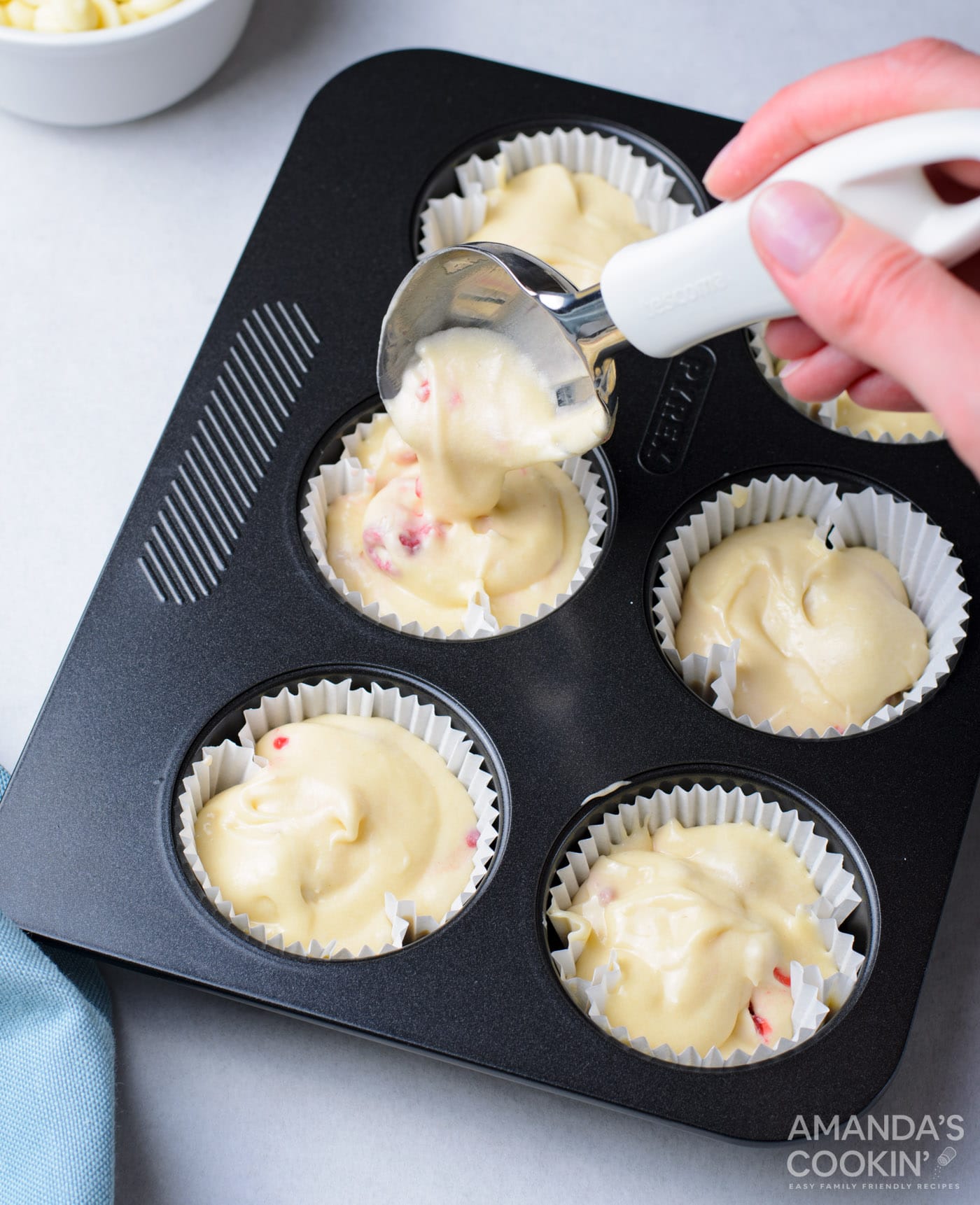 spoon filling cupcake liners with batter