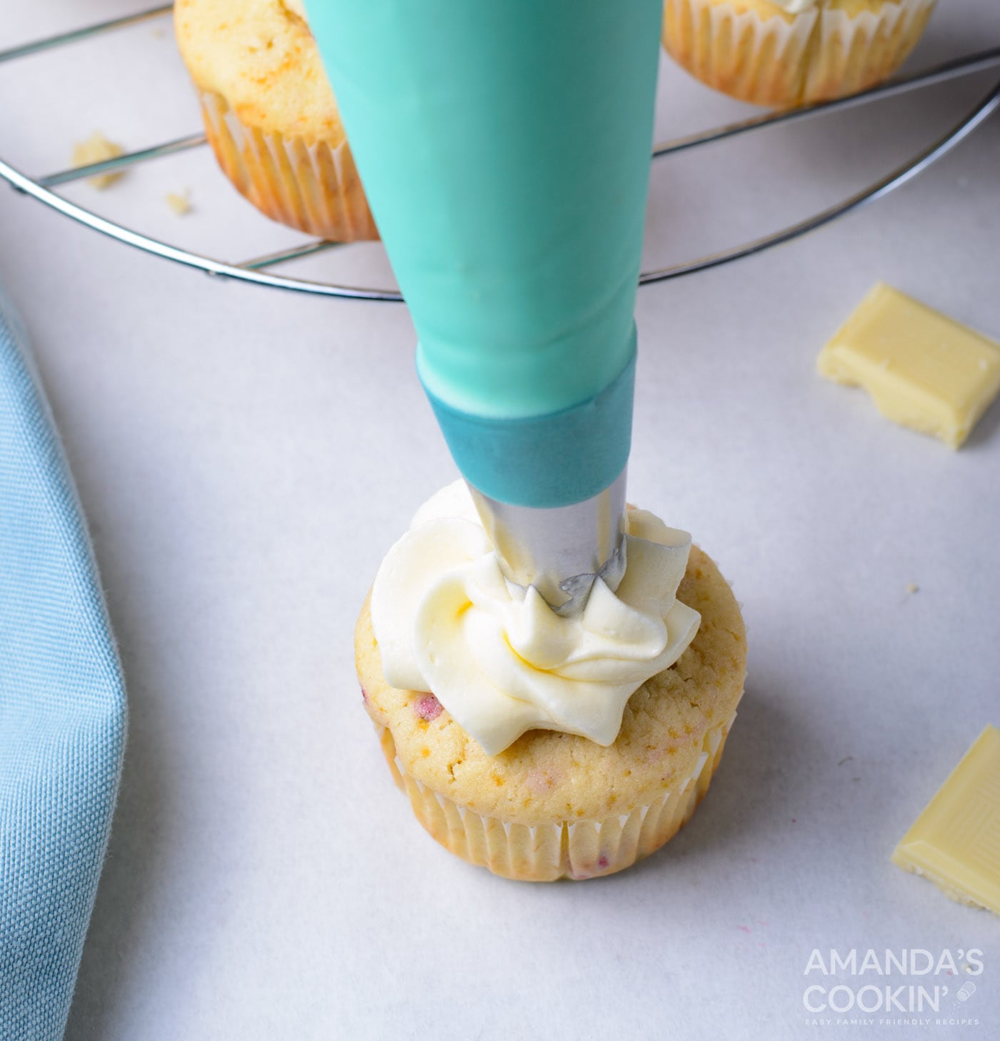 piping buttercream frosting onto cupcake