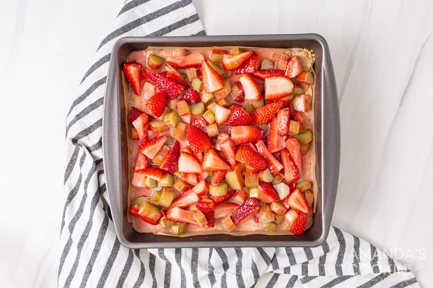 strawberries and rhubarb on top of crust in a pan