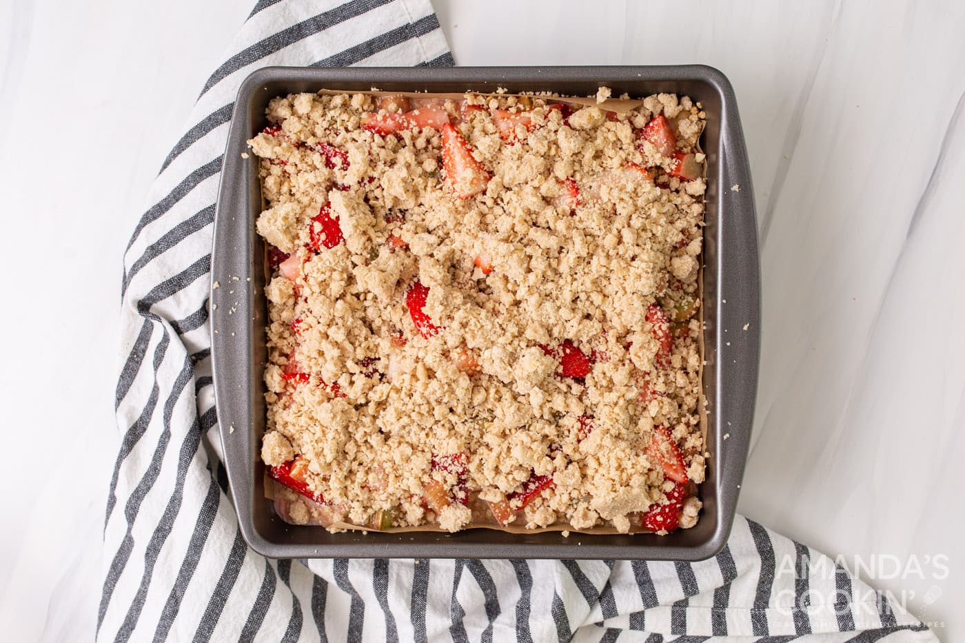 crumble topping over strawberry rhubarb crumble bars in a pan