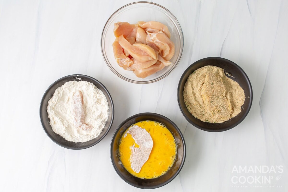 flour, eggs,, breadcrumbs, and chicken in bowls