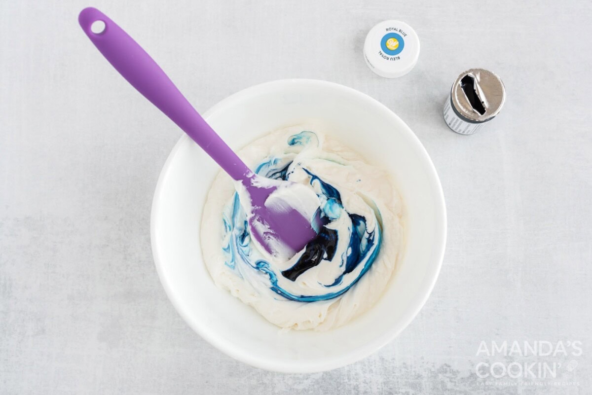 mixing blue food coloring into white frosting