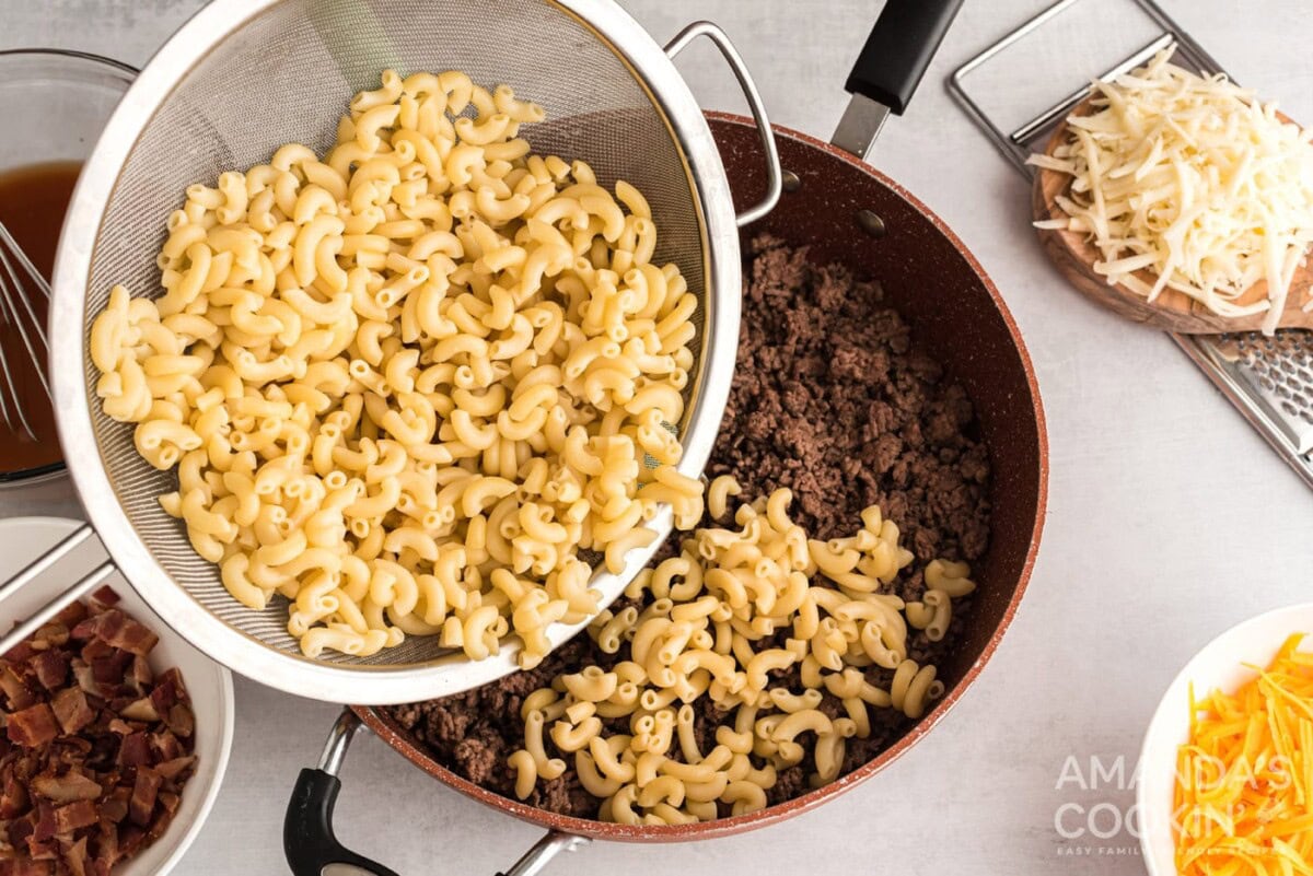 pouring drained pasta over beef mixture in skillet