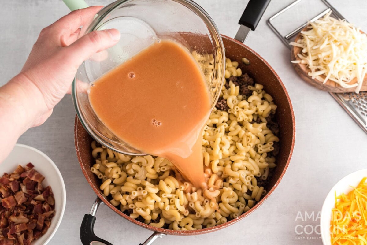 adding broth to skillet with pasta and ground beef