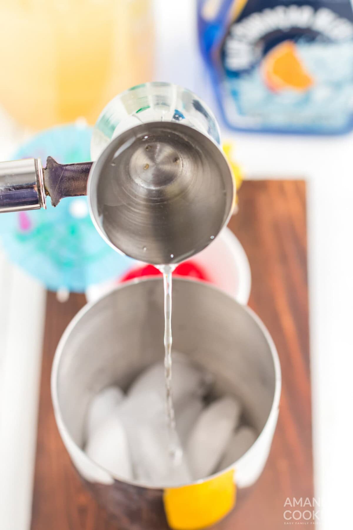 pouring vodka into cocktail shaker with ice