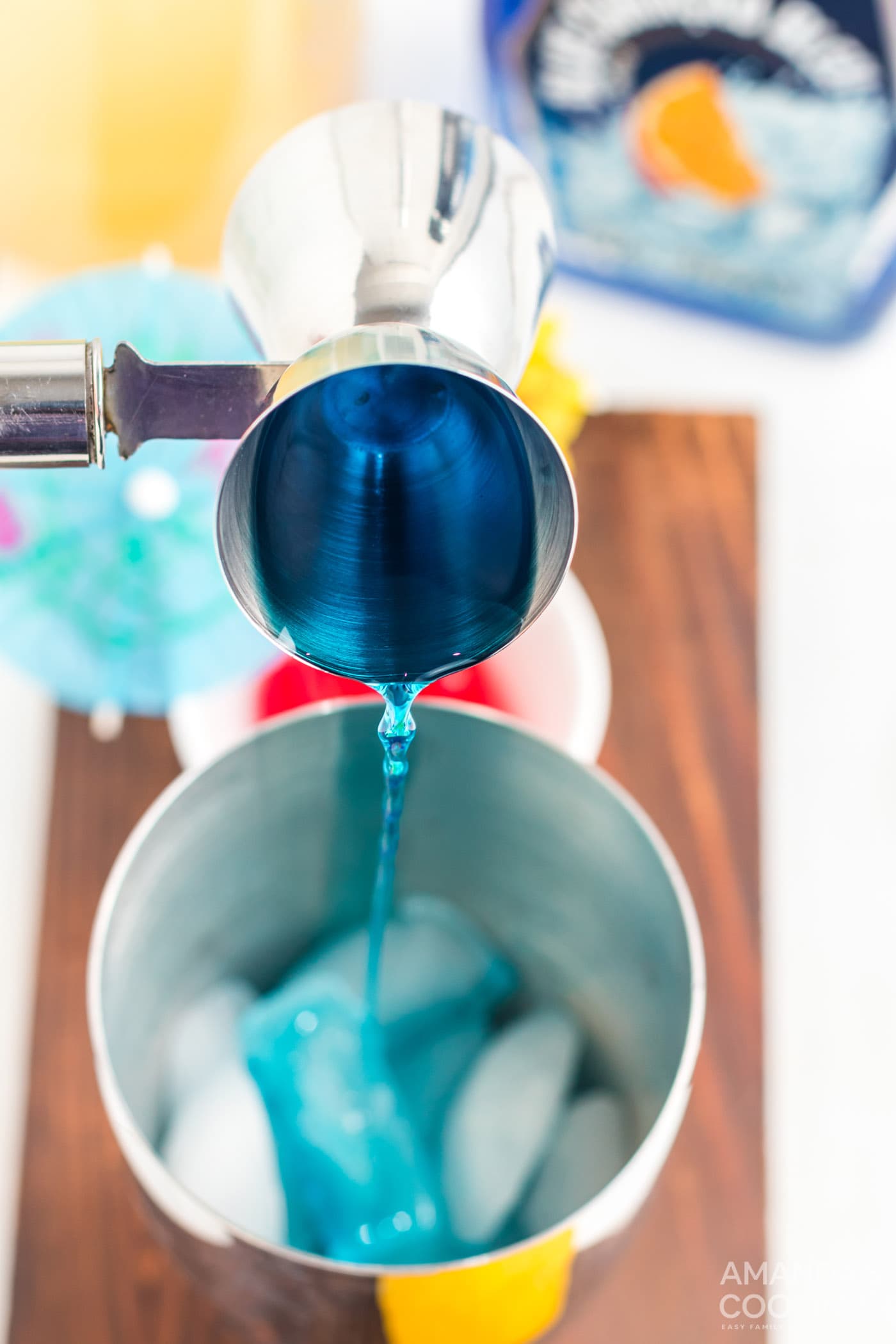 pouring blue Curacao into cocktail shaker with ice