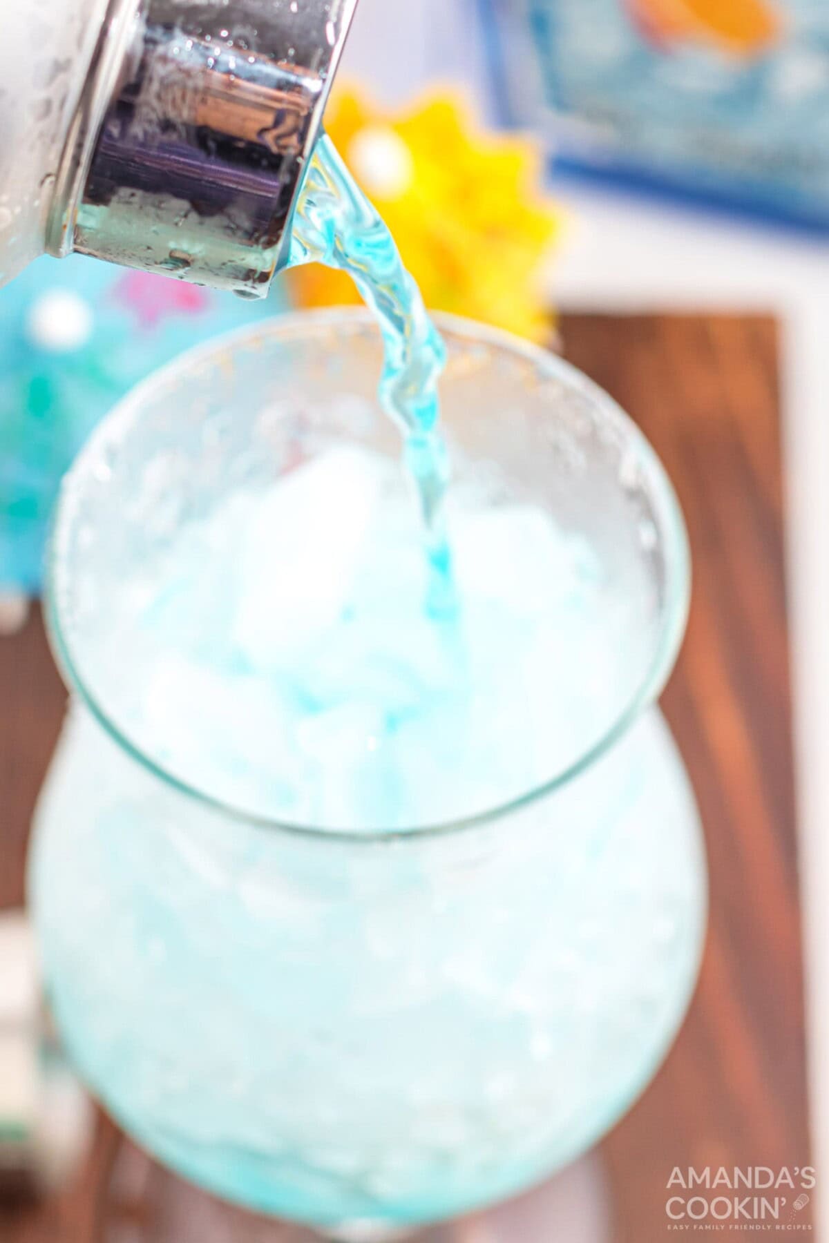pouring blue lagoon cocktail into a hurricane glass