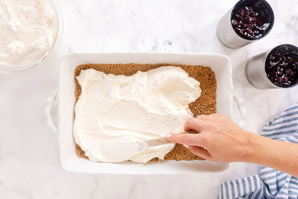 spreading cream cheese layer over crust