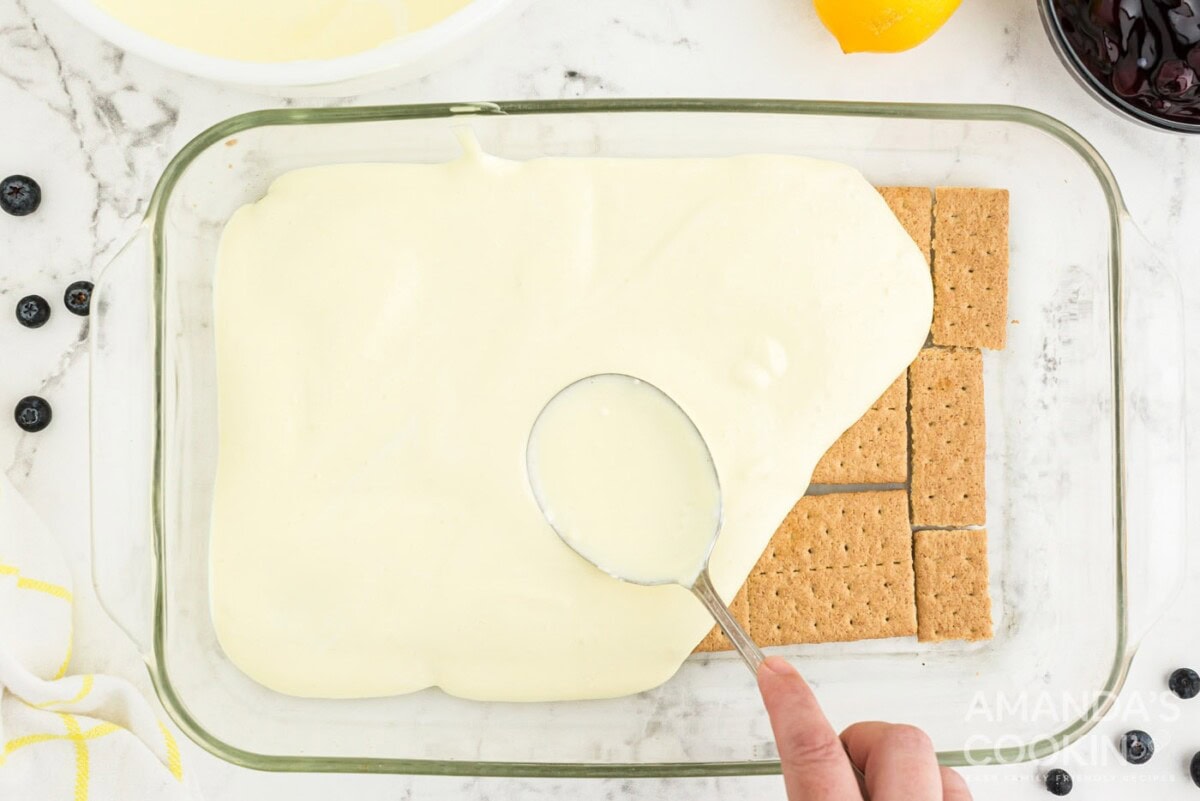 spooning pudding layer over graham crackers in casserole dish
