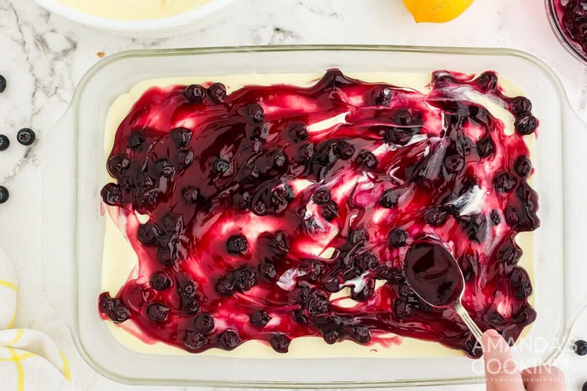spreading blueberry pie filling on top of pudding