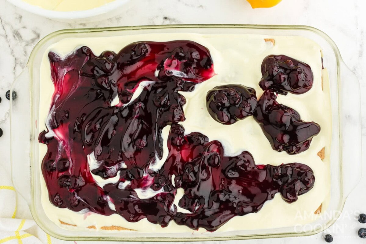 blueberry pie filling on top of pudding in a casserole dish