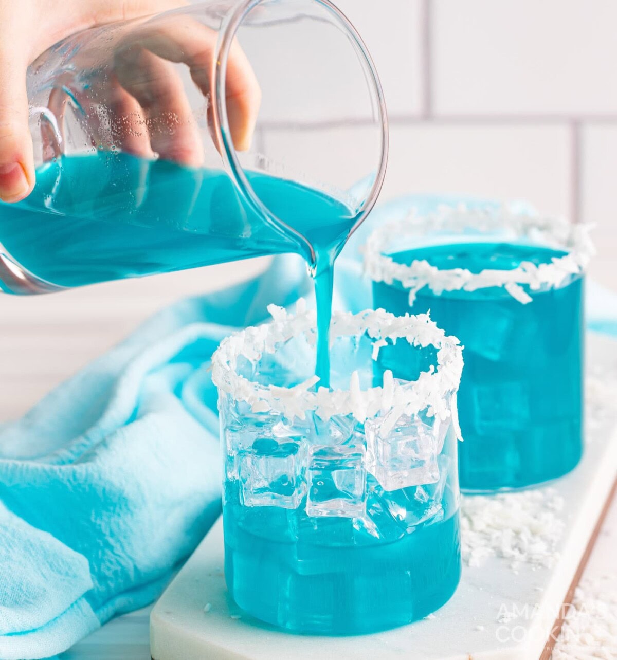 pouring ocean water cocktail into a glass with ice
